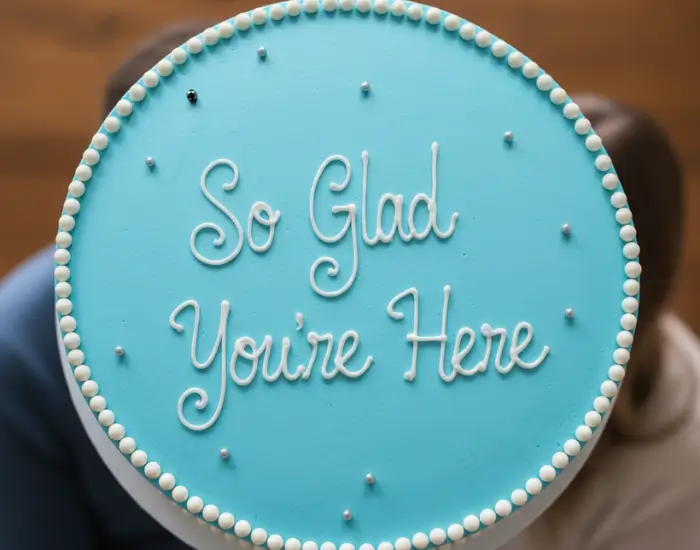 cake message written with white icing saying so glad you’re here